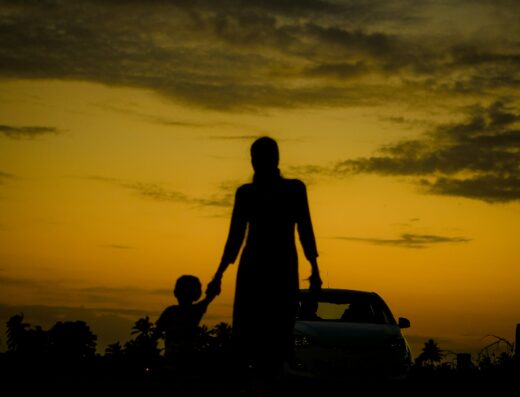 Silhouette einer Mutter mit Kind an der Hand im goldenen Abendlicht – Mama Coach am Traunsee