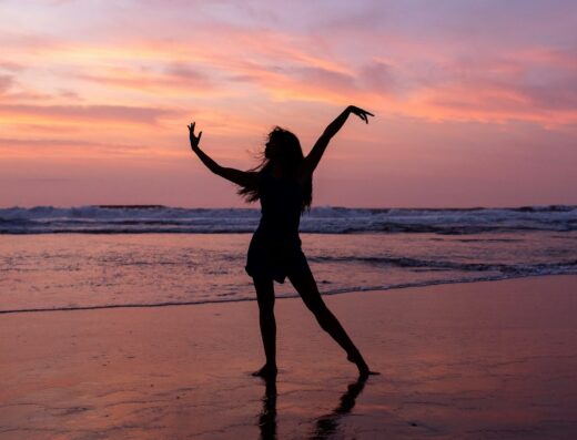 Silhouette einer tanzenden Frau am Strand bei Sonnenuntergang – Bewegung zur Musik beim Tae Bo